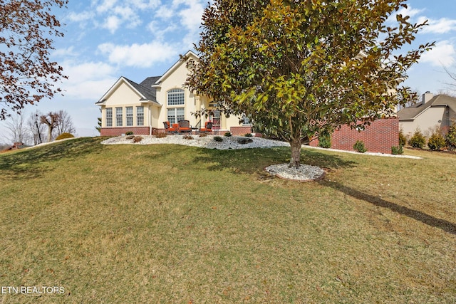 rear view of property featuring brick siding, a yard, and stucco siding