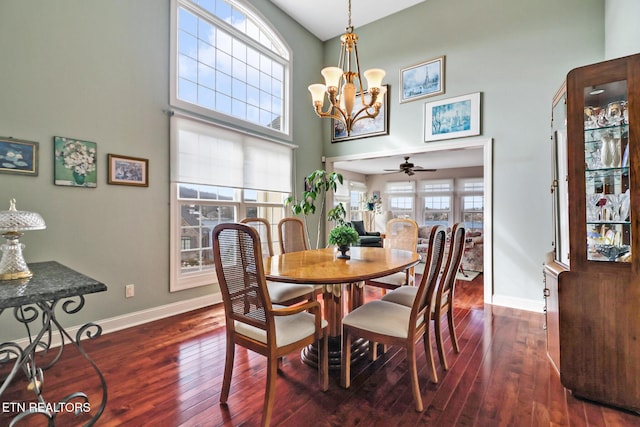 dining space with a notable chandelier, dark wood-type flooring, a high ceiling, and baseboards