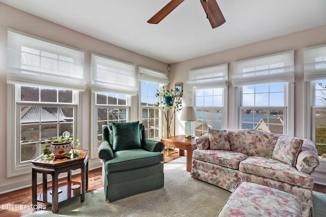 sunroom / solarium with a water view and a ceiling fan