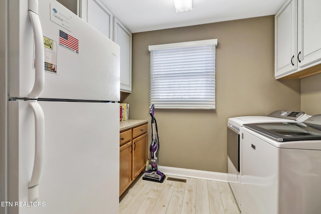 washroom with light wood-style floors, washer and dryer, visible vents, and baseboards