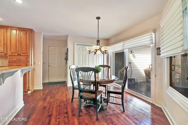 dining room featuring dark wood-style flooring, baseboards, and an inviting chandelier