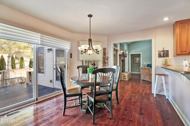 dining space featuring dark wood-type flooring, an inviting chandelier, visible vents, and baseboards