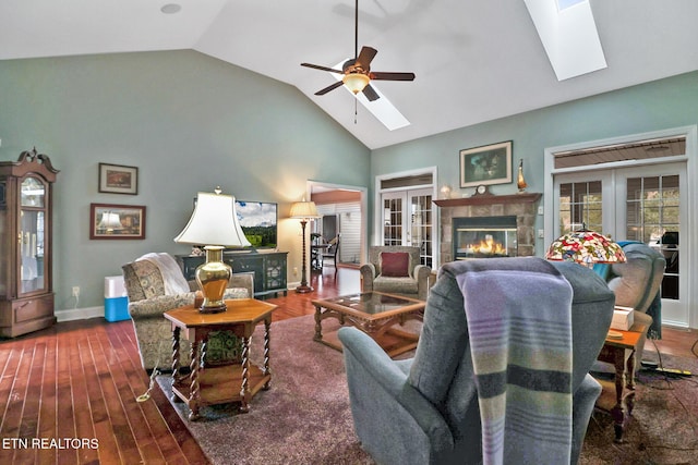 living room featuring a tiled fireplace, french doors, and a skylight