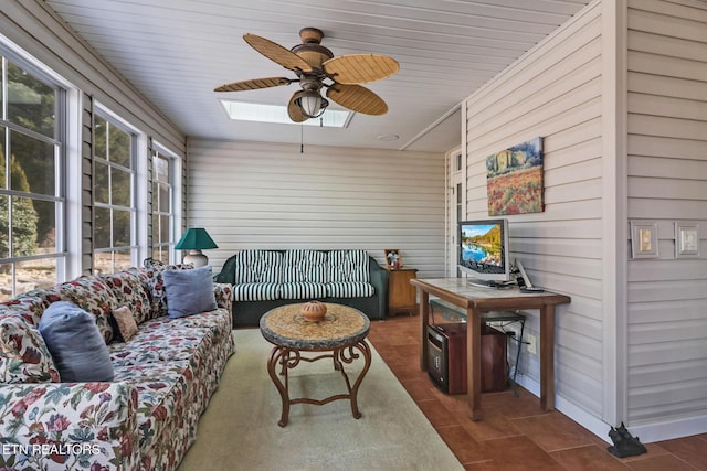 living room with ceiling fan and dark tile patterned flooring