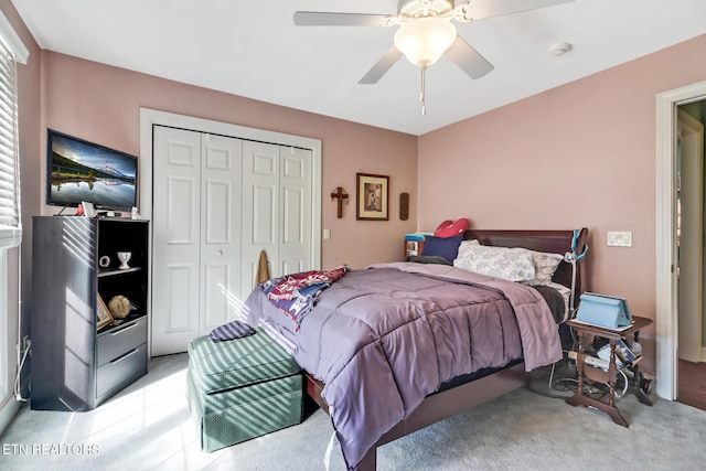 bedroom with a ceiling fan, a closet, and light carpet