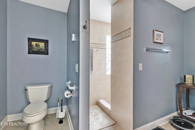 bathroom with a stall shower, baseboards, toilet, and tile patterned floors