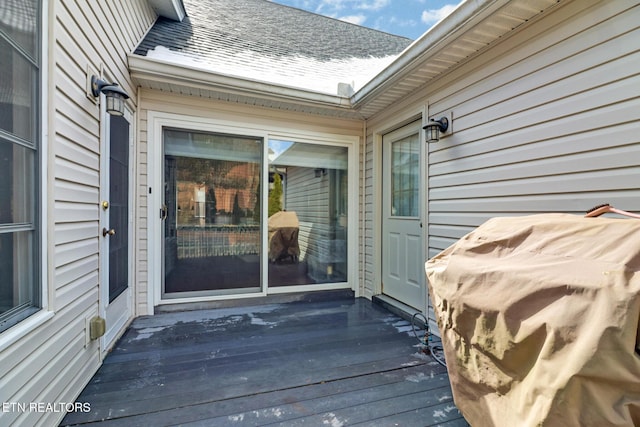 property entrance featuring a shingled roof and a wooden deck