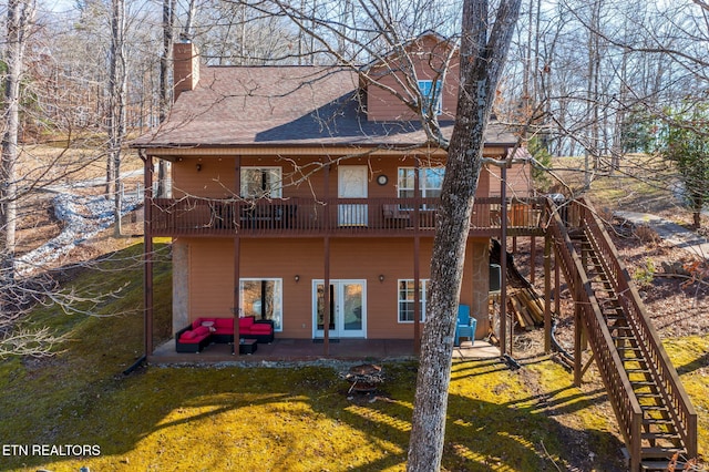 rear view of house with stairs, roof with shingles, a chimney, a patio, and a yard