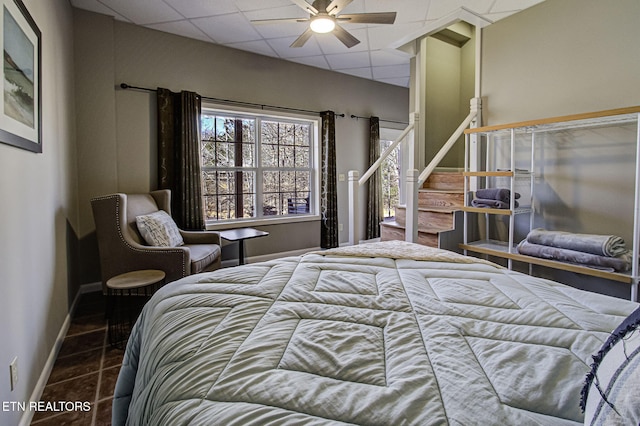 bedroom with baseboards, ceiling fan, tile patterned floors, and a paneled ceiling
