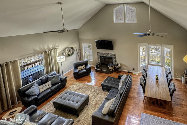 living room featuring baseboards, a fireplace, wood finished floors, and a ceiling fan