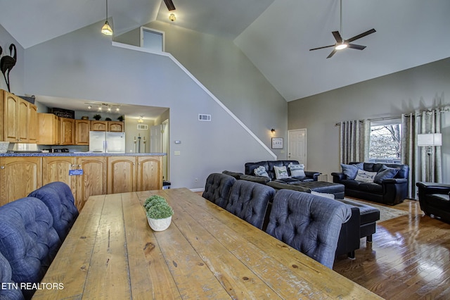 dining area featuring stairs, high vaulted ceiling, dark wood-style floors, visible vents, and a ceiling fan