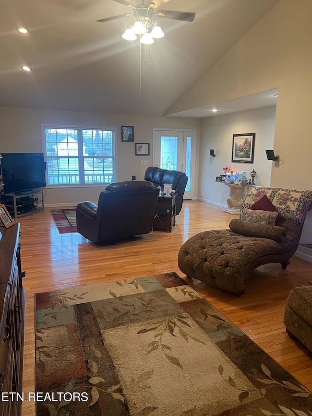 living room with ceiling fan, lofted ceiling, and light wood-type flooring