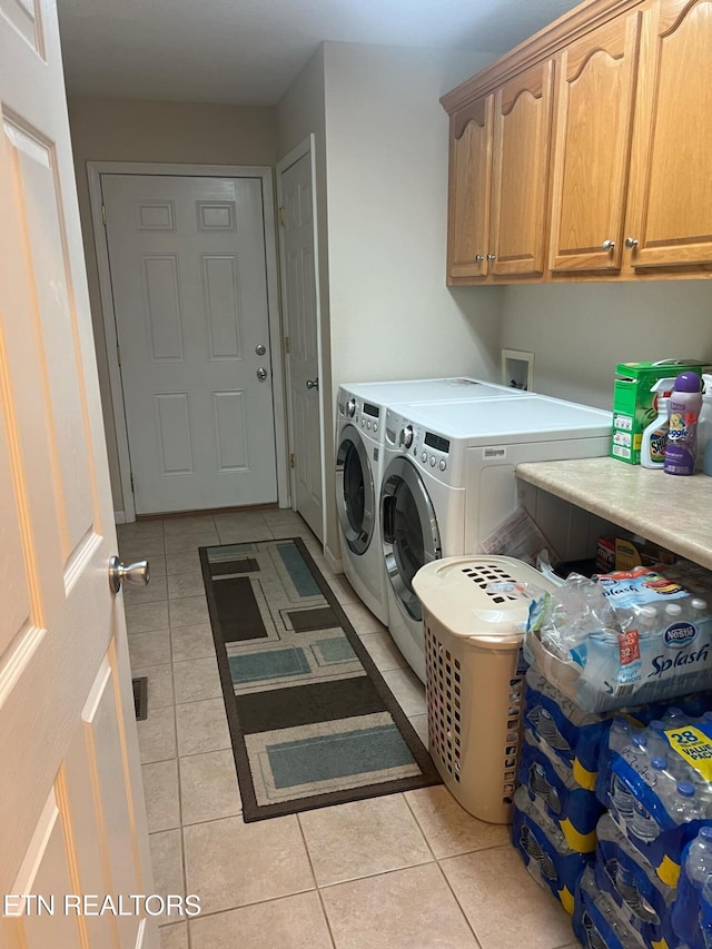 laundry room featuring cabinets, separate washer and dryer, and light tile patterned floors