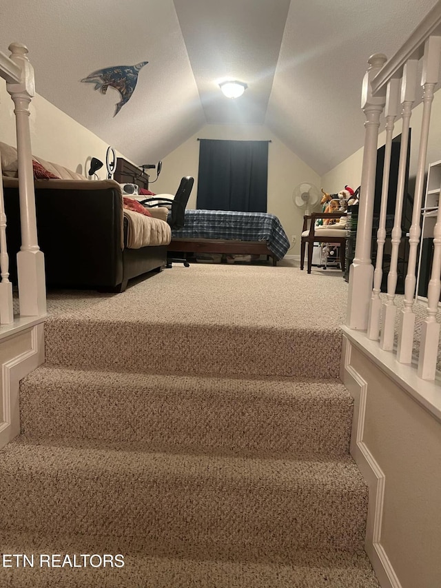 staircase with vaulted ceiling and carpet