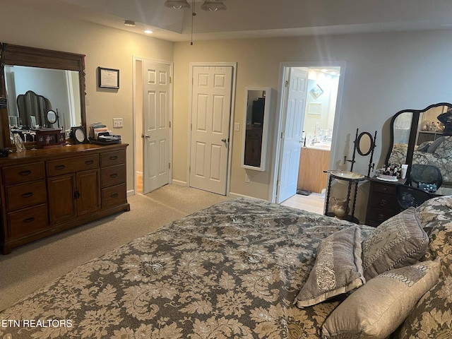 bedroom with ensuite bathroom and light carpet