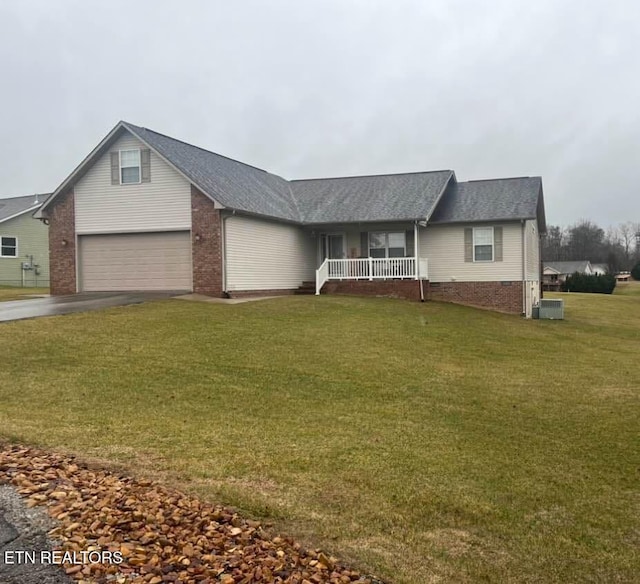 view of front of home with a porch, a garage, a front lawn, and central air condition unit