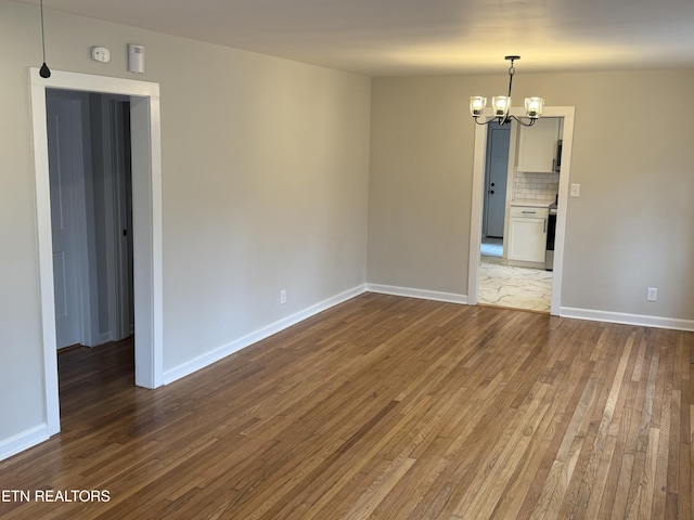 unfurnished room featuring a notable chandelier and wood-type flooring