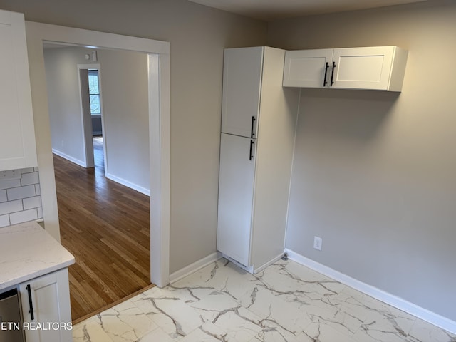 kitchen featuring white cabinetry and light stone countertops
