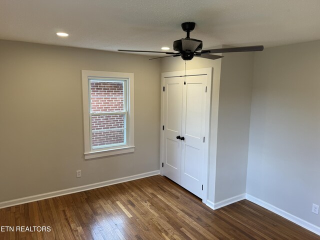 unfurnished bedroom with ceiling fan, a closet, a textured ceiling, and dark hardwood / wood-style floors