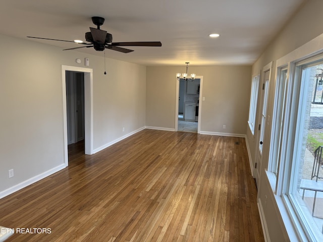 unfurnished room featuring ceiling fan with notable chandelier and hardwood / wood-style flooring