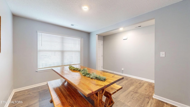 dining space with wood-type flooring and a textured ceiling