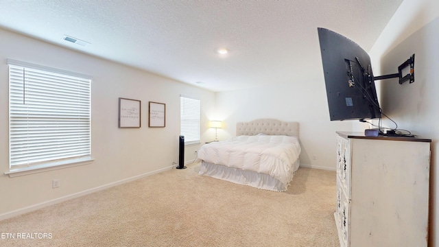 bedroom with light colored carpet and a textured ceiling