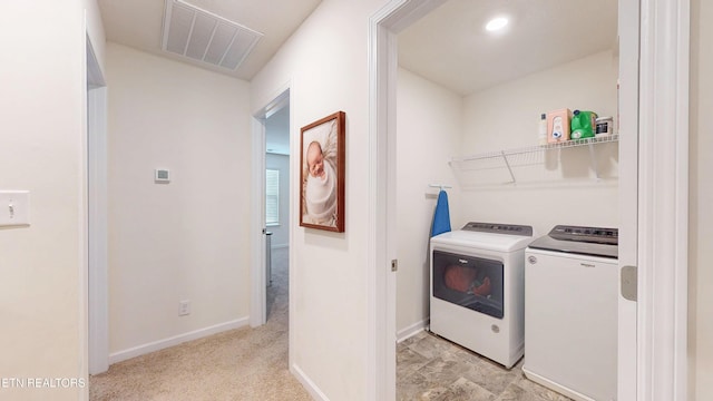 clothes washing area featuring light colored carpet and separate washer and dryer