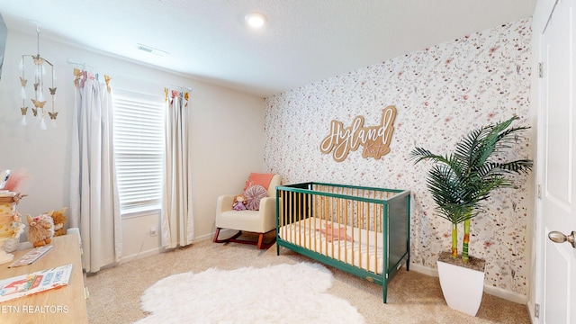 bedroom with a nursery area and carpet