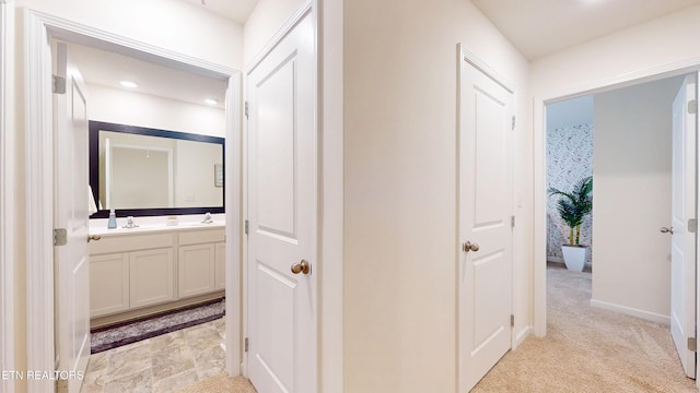 hallway featuring light colored carpet and sink