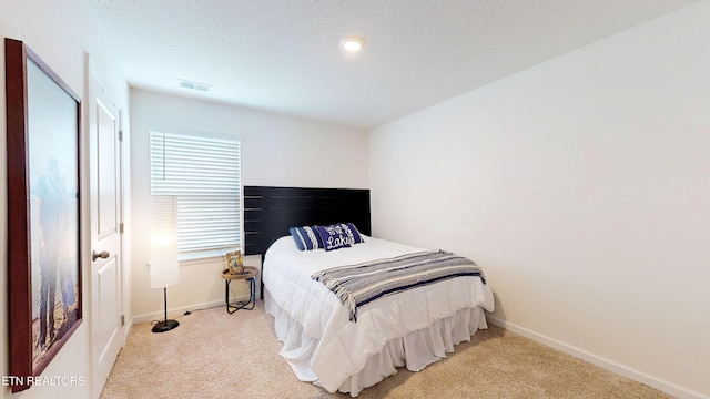 bedroom featuring light colored carpet and a textured ceiling