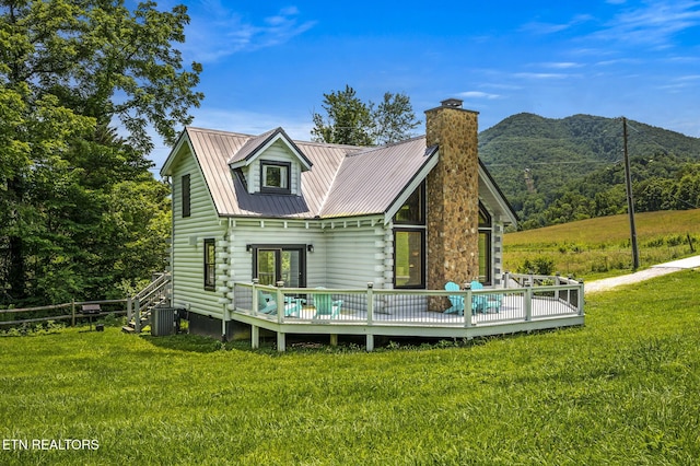 rear view of property with a deck with mountain view and a lawn