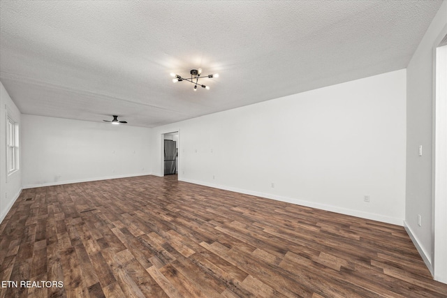 empty room with ceiling fan, dark hardwood / wood-style floors, and a textured ceiling