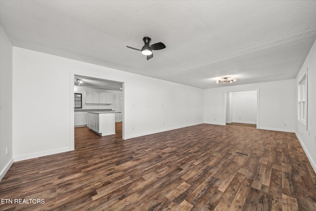 unfurnished living room featuring ceiling fan, a textured ceiling, and dark hardwood / wood-style flooring