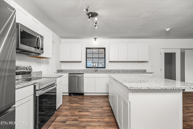 kitchen featuring dark hardwood / wood-style floors, white cabinetry, a center island, light stone counters, and stainless steel appliances