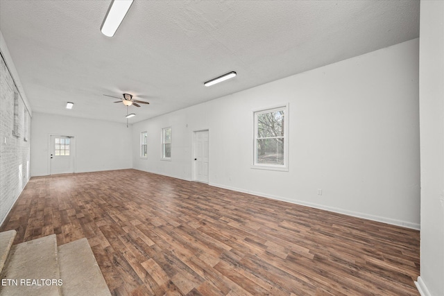 empty room with dark hardwood / wood-style flooring, a textured ceiling, and ceiling fan