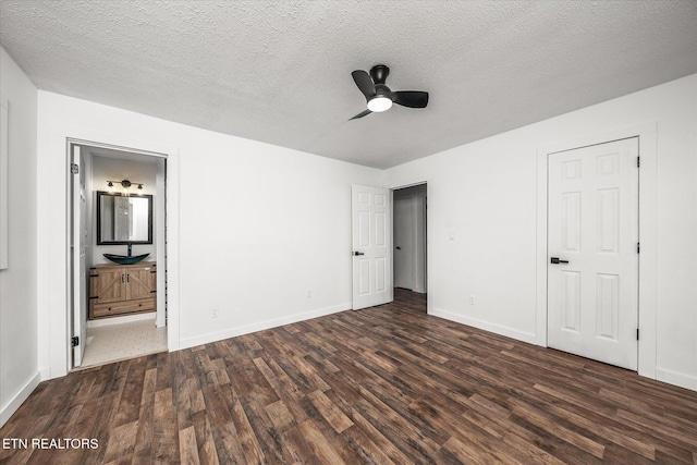 unfurnished bedroom featuring dark hardwood / wood-style flooring, ceiling fan, ensuite bath, and a textured ceiling