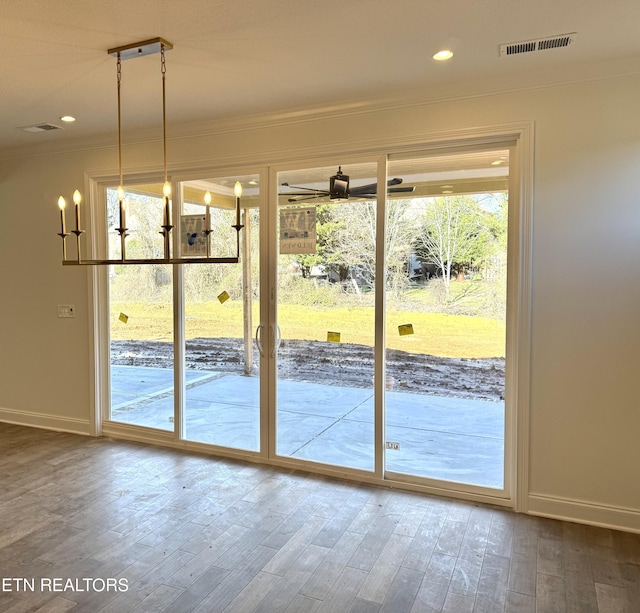 entryway with visible vents, baseboards, wood finished floors, and crown molding