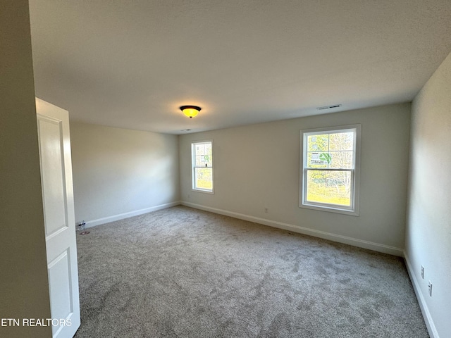 carpeted spare room featuring visible vents and baseboards