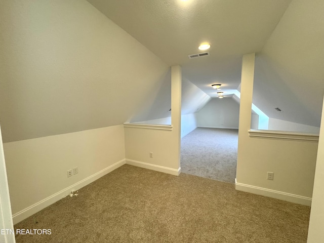 additional living space with visible vents, lofted ceiling, baseboards, and carpet flooring