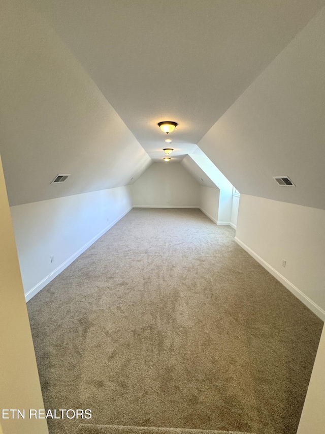 bonus room with lofted ceiling, visible vents, baseboards, and carpet floors