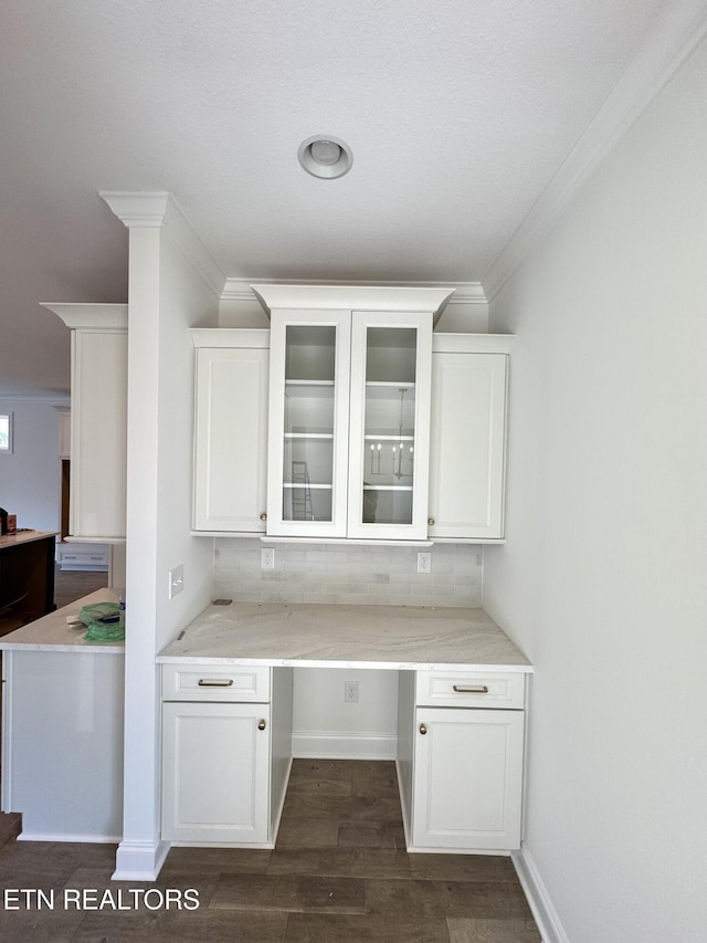 unfurnished office featuring built in study area, crown molding, baseboards, and dark wood-style flooring