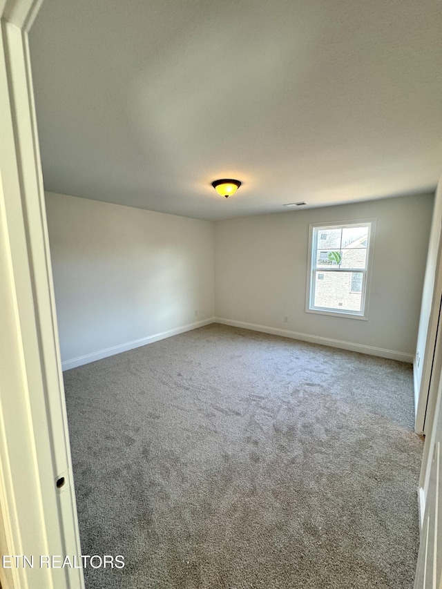 carpeted spare room with visible vents and baseboards