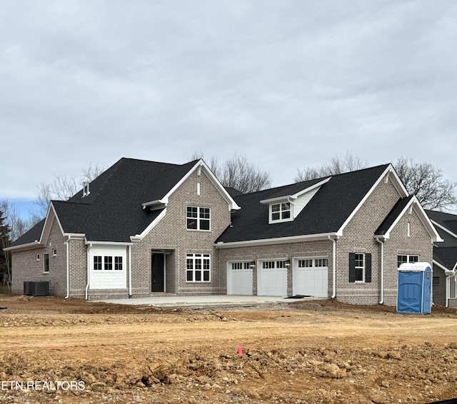 traditional-style home with cooling unit, brick siding, a garage, and driveway