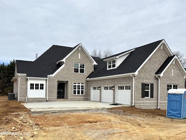 view of front facade featuring central air condition unit, an attached garage, brick siding, and driveway