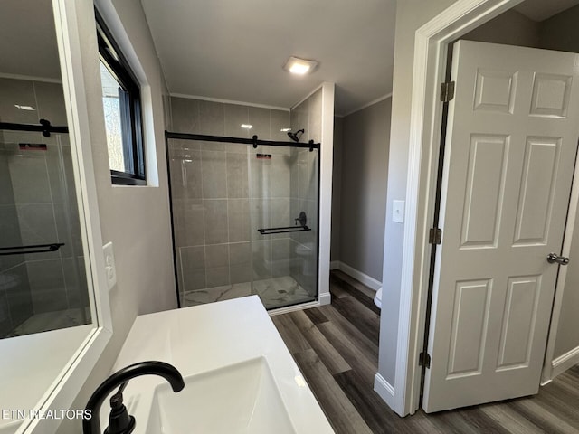 bathroom with hardwood / wood-style flooring, ornamental molding, and an enclosed shower