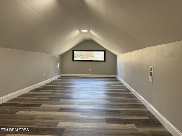 bonus room featuring dark wood-type flooring and vaulted ceiling