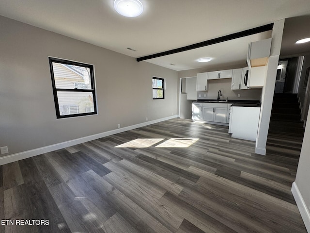 kitchen with beamed ceiling, sink, white cabinets, and dark hardwood / wood-style floors