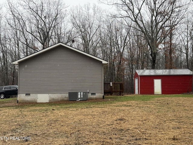 view of side of home with an outdoor structure, a yard, and central air condition unit