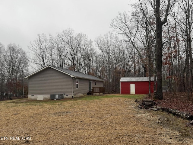 view of side of home featuring a yard, an outdoor structure, and central air condition unit