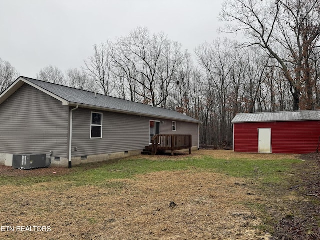 back of property featuring an outbuilding, a yard, a deck, and central air condition unit